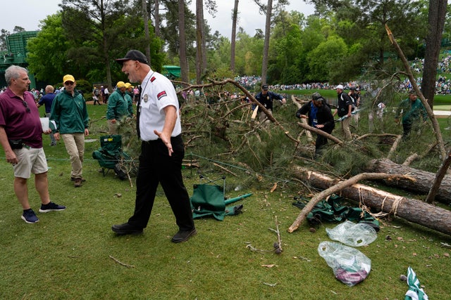 A security guard is seen moving people away from a tree that blew over on the 17th hole at the Masters golf tournament.
