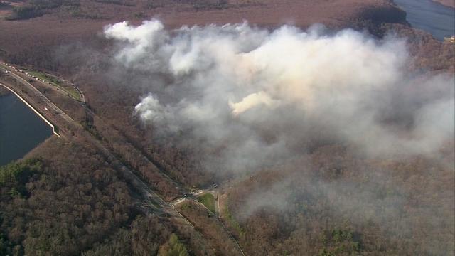 An aerial view of a large cloud of smoke over a wildfire in a wooded area of West Milford. 