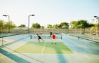 Extreme wide shot of senior friends playing doubles pickleball on sunny summer evening 