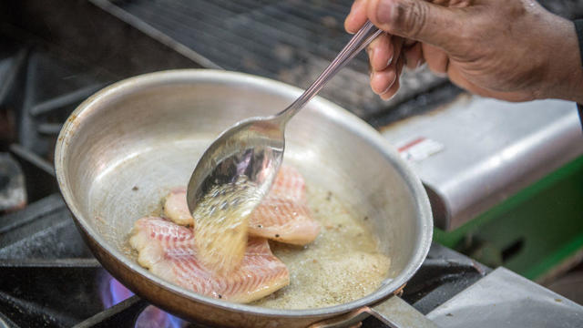 Local, sustainably-sourced blue catfish being pan-seared and coated in a butter sauce 