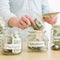 Teenage girl (16-17) filling jars with various labels with US dollars 