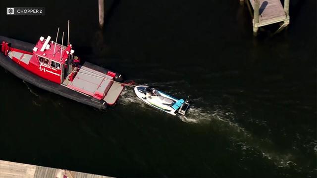 A boat tugs a Jet ski craft toward docks. 
