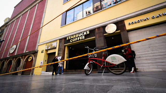 People wearing face masks walk past Starbucks coffee in 