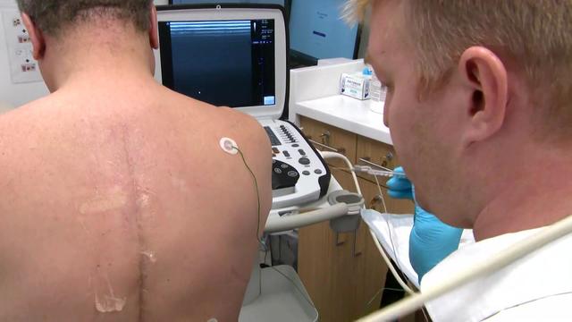 A doctor examines a scar on Sydney Martin's back. 