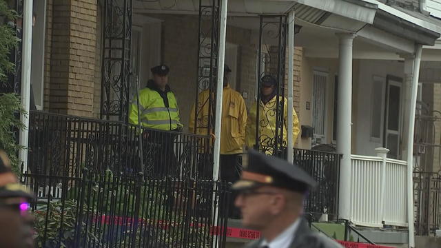 police officials standing on a porch as rain falls 