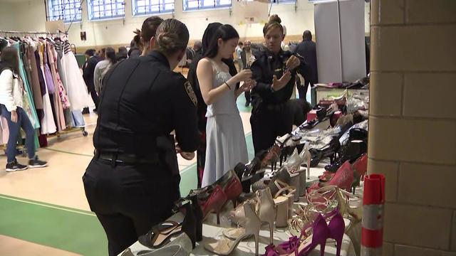 NYPD officers held students pick out accessories while standing in front of a table full of shoes. 