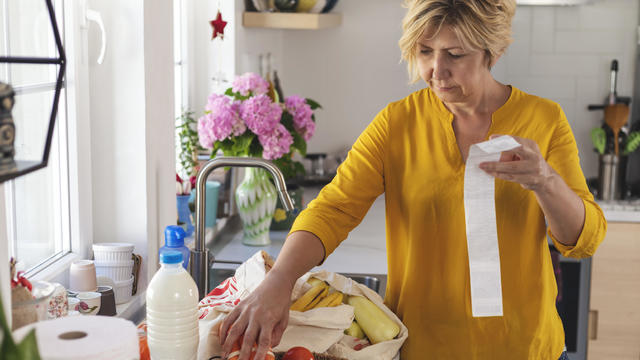 Shoot of woman going through her receipts at home after buying groceries 