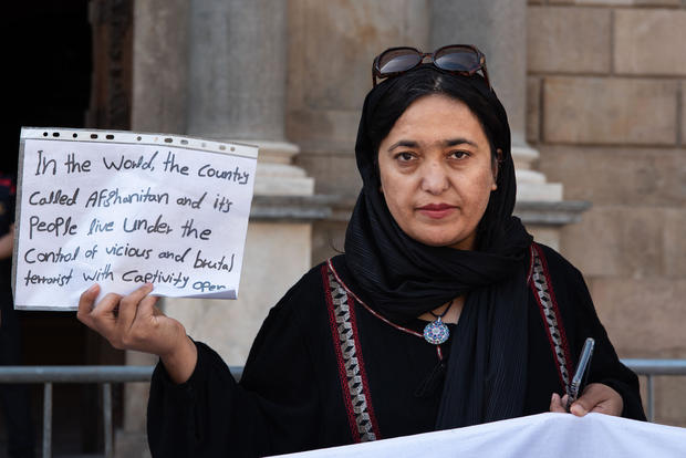 An Afghan woman holds a placard with a message "In the world 