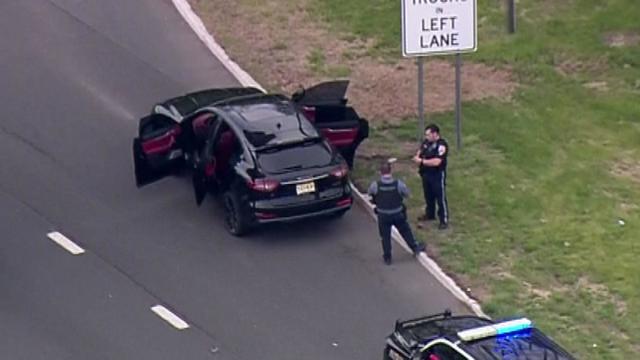 An aerial view of officers standing next to a Maserati with all of its doors open. 