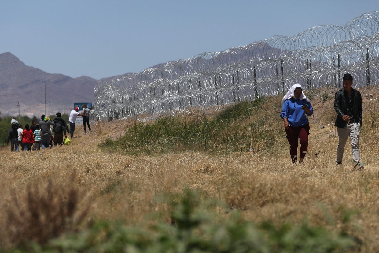 Migrants cross through the banks of the Rio Grande to be processed by the Border Patrol in Texas after crossing from Ciudad Juárez, Mexico, on May 9, 2023.  