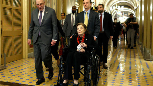 Senate Majority Leader Charles Schumer escorts Sen. Dianne Feinstein as she arrives at the U.S. Capitol following a long absence due to health issues on May 10, 2023. 