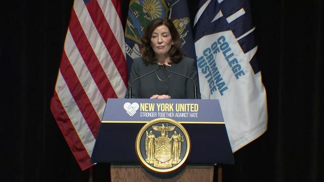 Gov. Kathy Hochul stands on a stage behind a podium. 
