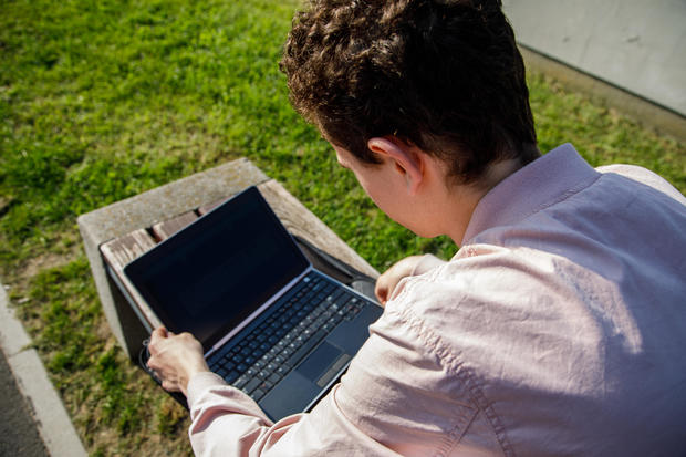 Teen with MacBook in park 