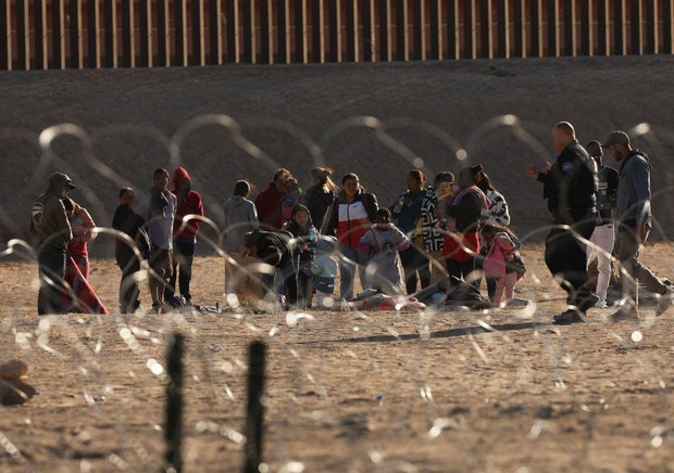 Migrants wait on the banks of the Rio Grande to be processed by the Border Patrol in Texas after crossing from Ciudad Juárez, Mexico, on May 11, 2023.
