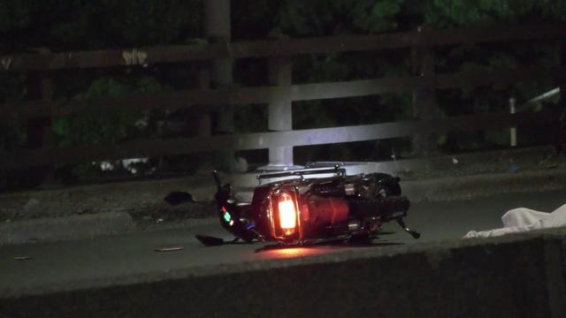 An electric motorcycle lies in the road on the Cross Bronx Expressway. 