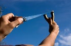 A rock is pulled back in an sling shot pointed to the sky 