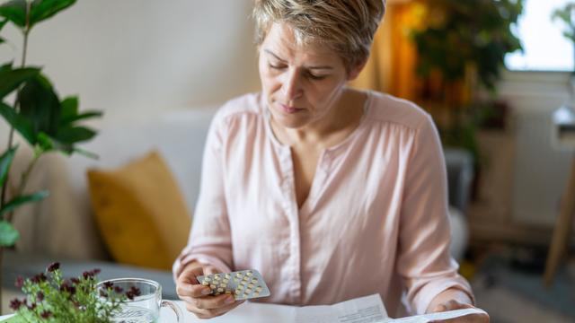 Holding blister pack with pills in hand and reading medical instructions 