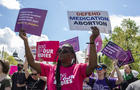Activists holding abortion rights signs shout slogans during 