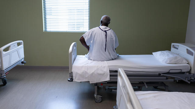Older man sitting on a hospital bed 