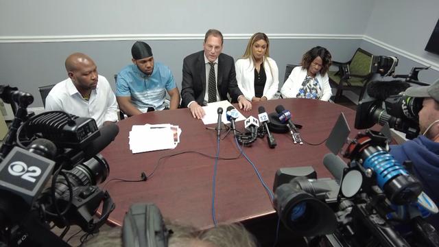 Warren Whyte, Warren Whyte Jr., attorney Kenneth Mollins, Sherene Whyte and Iceline Nelson sit at a table in front of cameras and microphones. 