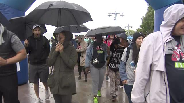 People, some with umbrella, participate in the 2023 Great Strides walk. 
