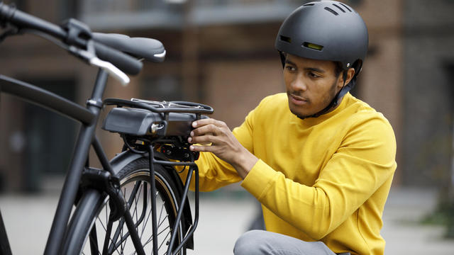 Young man changing battery pack on electric bicycle 
