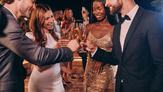 Group of people in formalwear toasting with champagne and smiling 