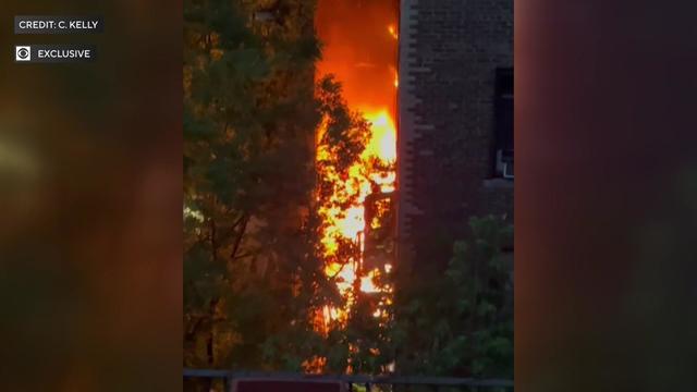 Flames can be seen engulfing the first floor of an apartment building. 