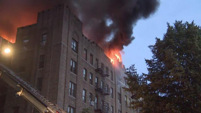Flames and smoke billow from the top of a Bronx apartment building. 