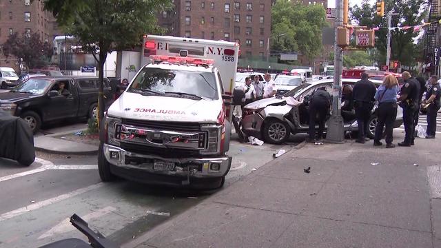 A silver SUV and an ambulance, both with damage, sit on the curb of a street. 