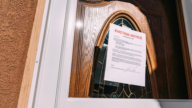Low Angle Shot of a Paper Eviction Notice Taped to the Glass Front Door of a Rental Home in a Residential Suburban Neighborhood 