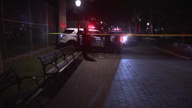 Crime scene tape blocks off park of Thomas Jefferson Park. NYPD officers stand near an NYPD vehicle. 
