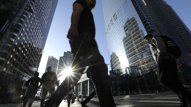 People walk on a crosswalk by skyscrapers 