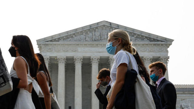 A group of people wear face masks to protect against air pollution as they walk past the Supreme Court Building on June 29, 2023, in Washington, D.C. 