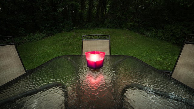 Candle lit glass table in private backyard 
