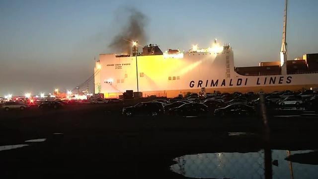 Crews battle a fire on a cargo ship with "Grimaldi Lines" painted on the side. 