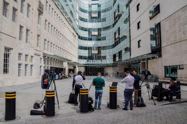 Members of the media gather outside Broadcasting House, the