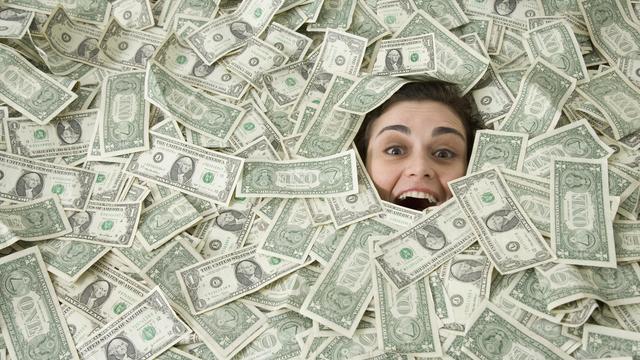 Woman's face peeking out of a pile of money 