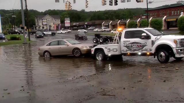 A tow truck tows a sedan out of a flooded road in Waterbury. 