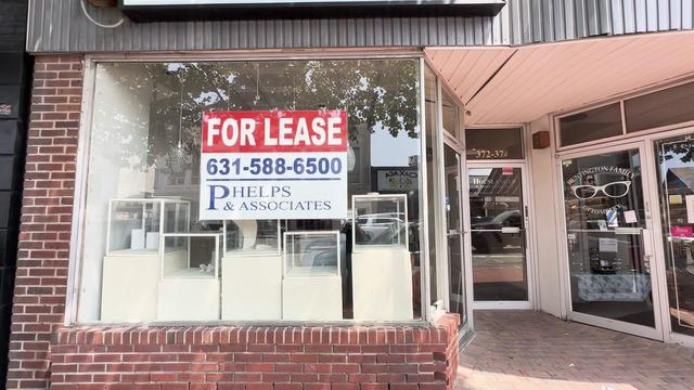 An empty storefront with jewelry display boxes in the window and a "for lease" sign. 