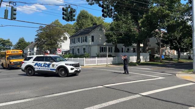 A New Rochelle police officer stands in the middle of an intersection to direct traffic underneath a traffic light that's out. 