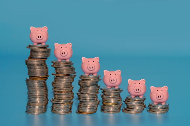 Piggy banks standing on top of stacks coins. 