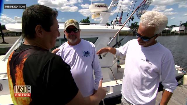 Three men stand on a dock near a boat. 