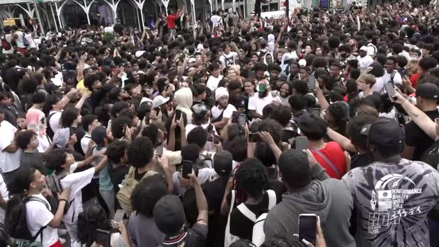 Hundreds of people crowd and point their phones at an individual in Union Square. 