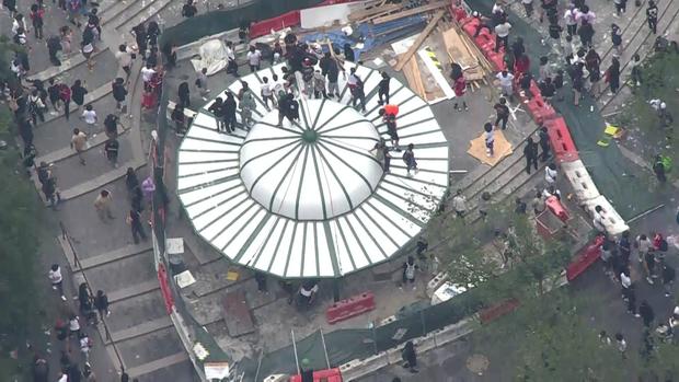 An aerial view of thousands of people crowded into Union Square. A number of people have climbed onto the roof of a structure. 