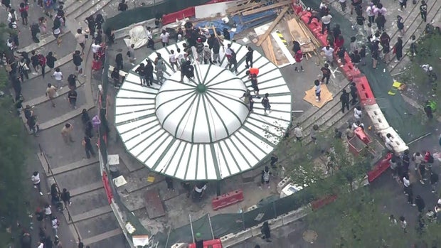 An aerial view of thousands of people crowded into Union Square. A number of people have climbed onto the roof of a structure.