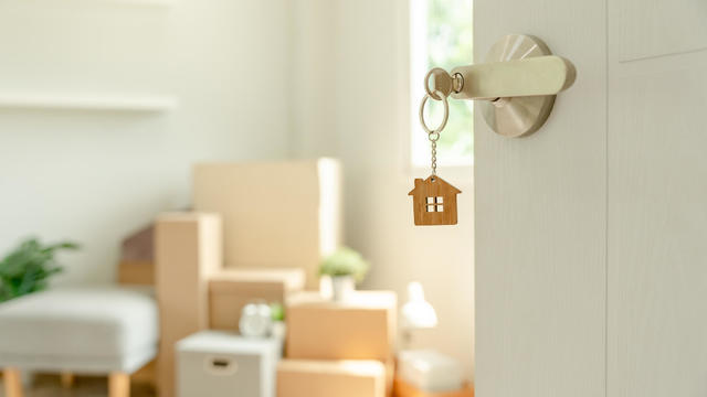 Moving house, relocation. The key was inserted into the door of the new house, inside the room was a cardboard box containing personal belongings and furniture. move in the apartment or condominium 