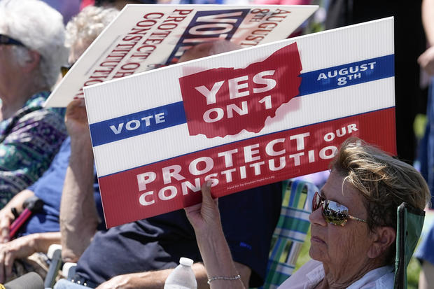 An attendee uses a sign to shield the sun during a rally on Sunday, Aug. 6, 2023, in Norwood, Ohio. 