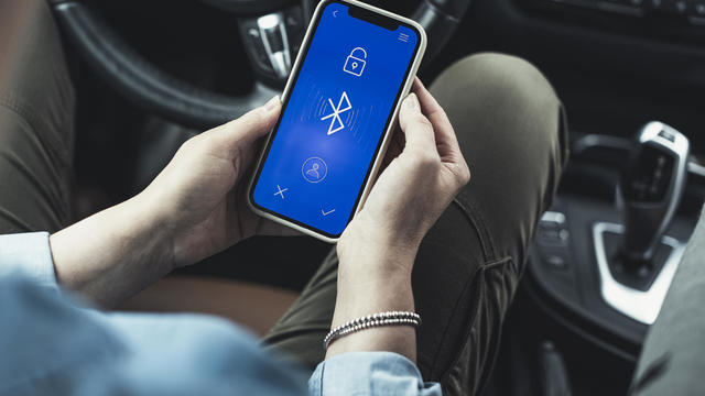 Woman accessing bluetooth on mobile phone in car 