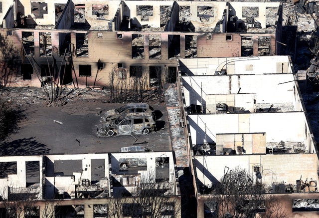 Burned cars sit in front of an apartment building that was destroyed by a wildfire in Maui 